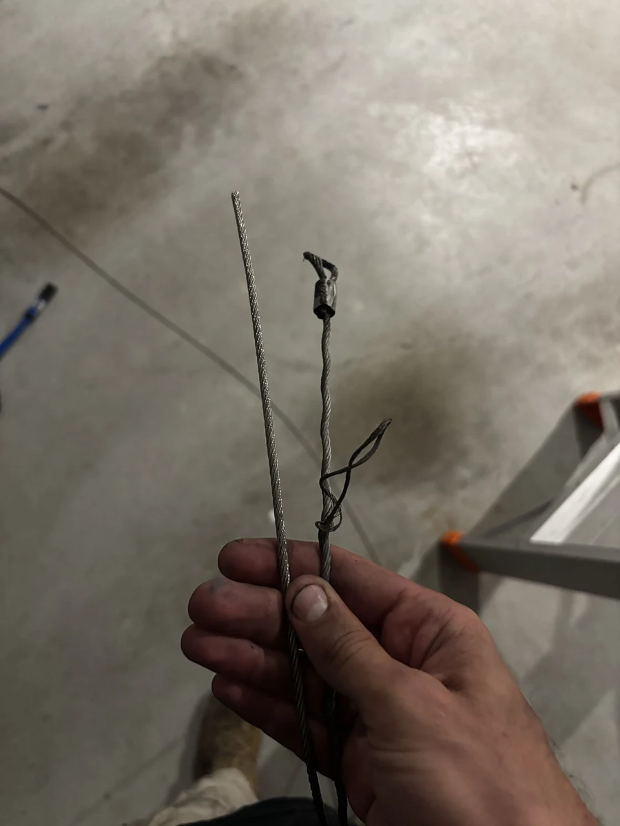 A snapped garage door cable next to an intact one